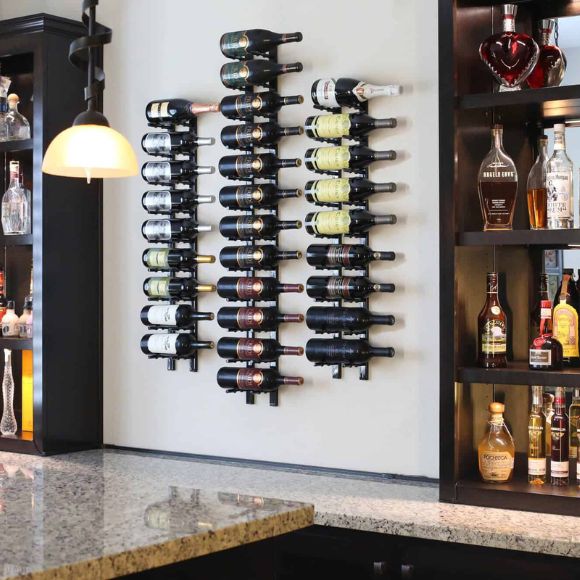 Wine bottles arranged on a wall-mounted rack in a bar setting.