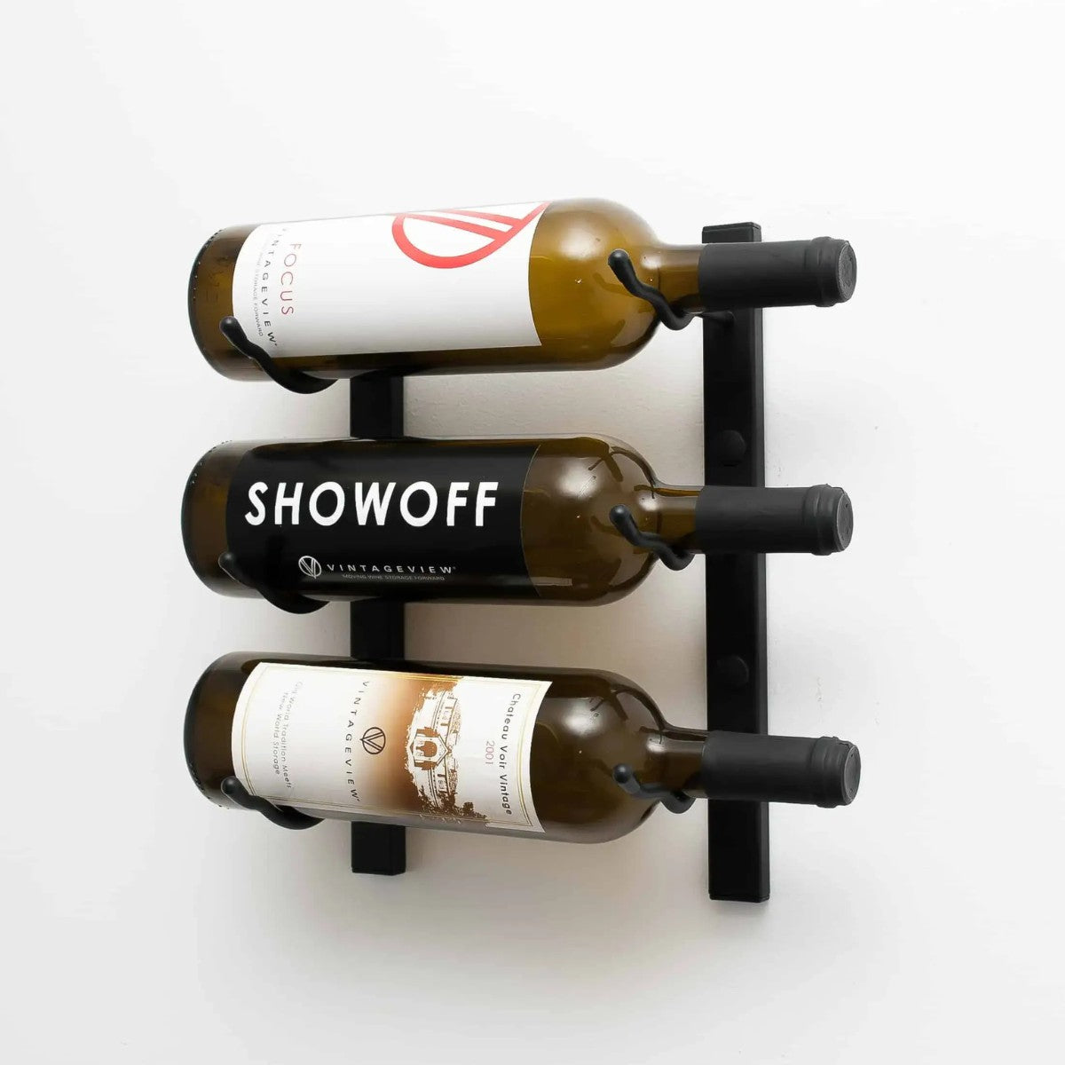 Wall-mounted wine rack holding three bottles with visible labels on a white background