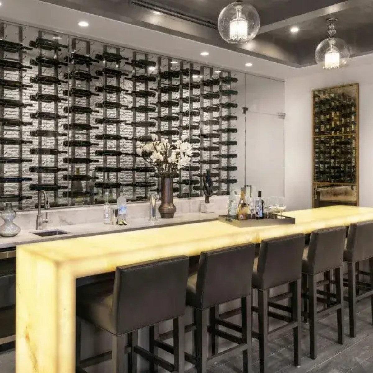 Modern bar with wine bottles on the wall and a long counter.