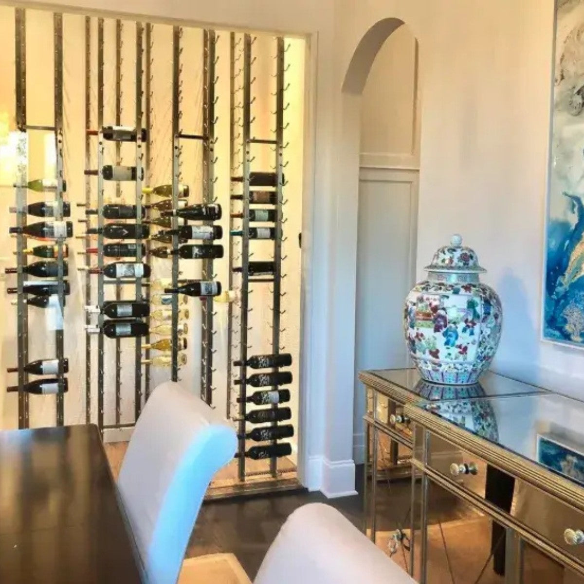 Wine rack with bottles in a room with a decorative vase and mirror.