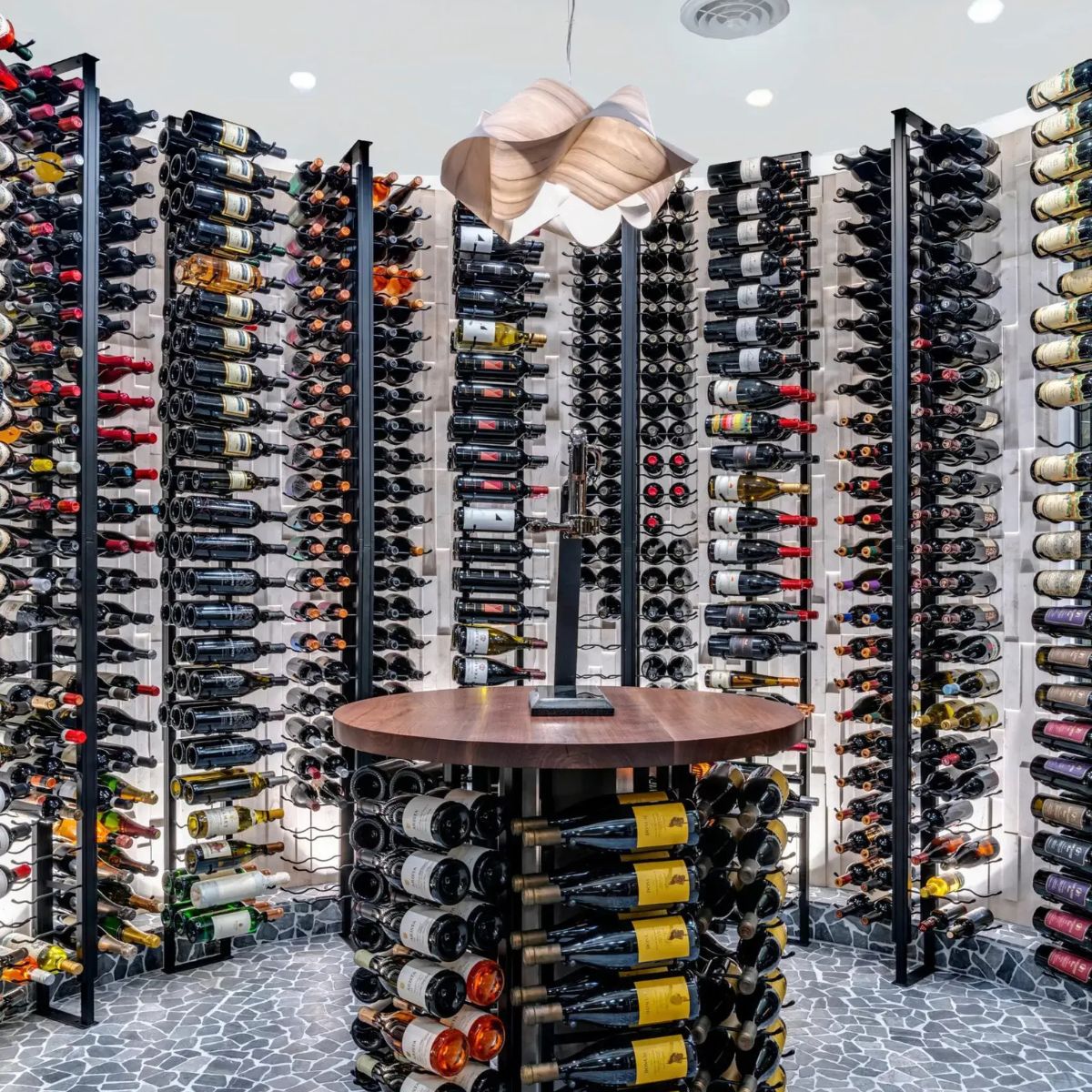 Wine cellar with rows of wine bottles on racks and a small round table in the center.
