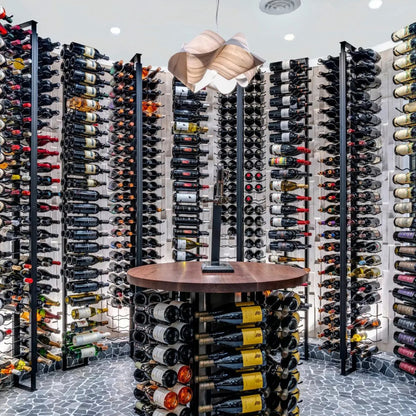 Wine cellar with rows of wine bottles on racks and a small round table in the center.