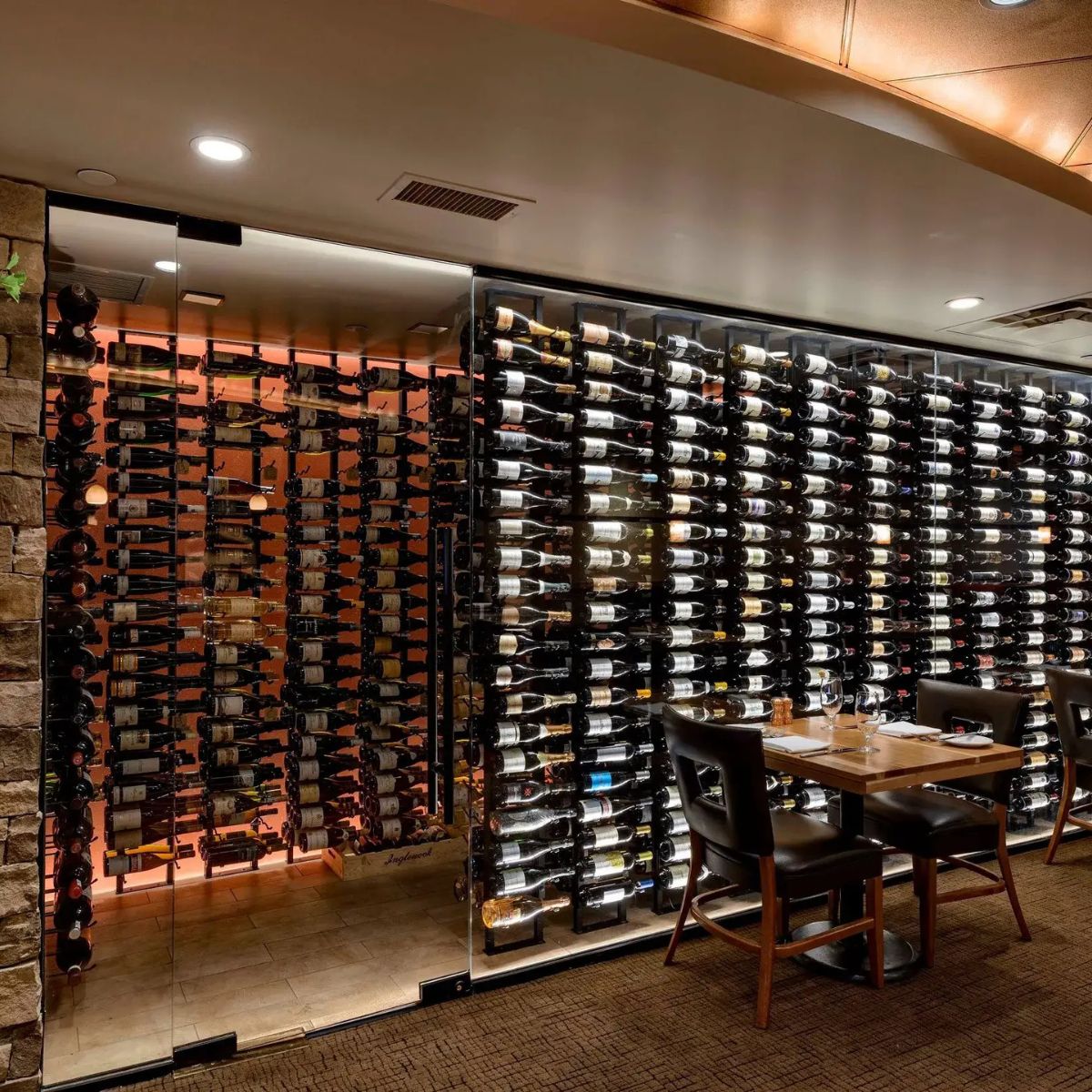 Wine cellar with a wall of wine bottles and a dining table.