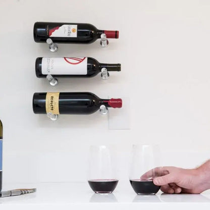 Clear acrylic wine pegs mounted on wall above counter with wine glasses for modern minimalist storage