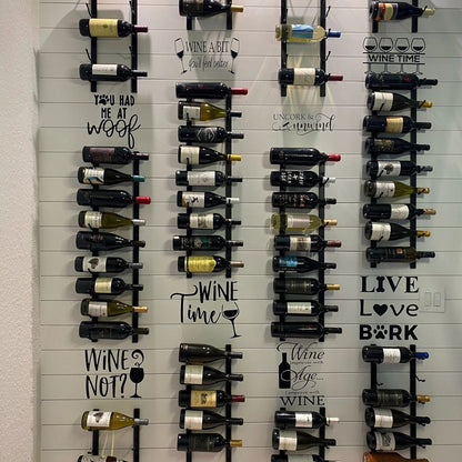 Wall-mounted wine rack with various wine bottles and decorative text labels.
