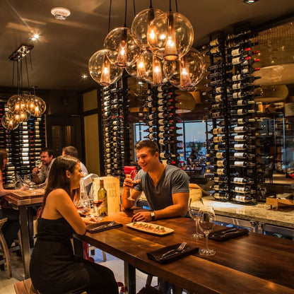 People dining at a restaurant with wine bottles and chandelier in the background
