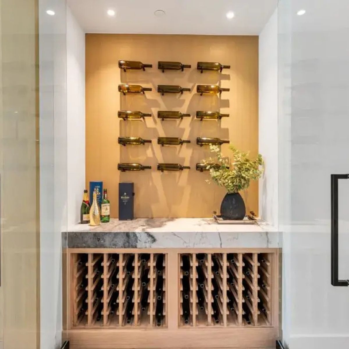 Wine bottles displayed on a wall-mounted rack with a wine cabinet below.